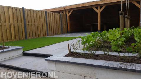Tuin met kunstgras, hout beton schutting en houten overkapping