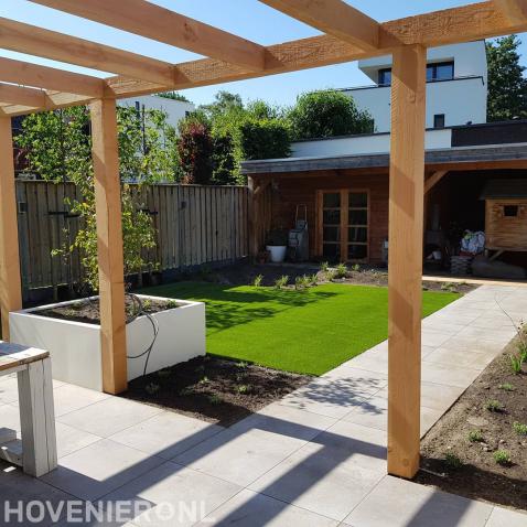 Moderne tuin met kunstgras, terrasoverkapping en witte plantenbakken 2