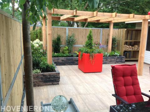 Onderhoudsvriendelijke tuin met houten pergola en rode plantenbakken 2