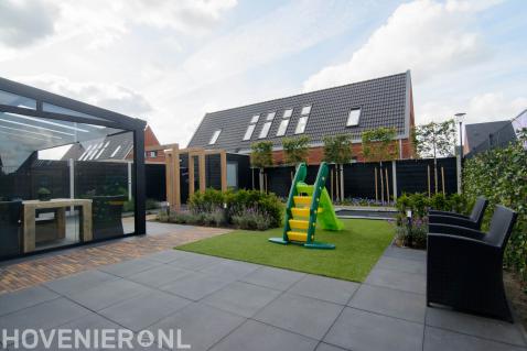 Kindvriendelijke tuin met kunstgras, trampoline, pergola en leibomen
